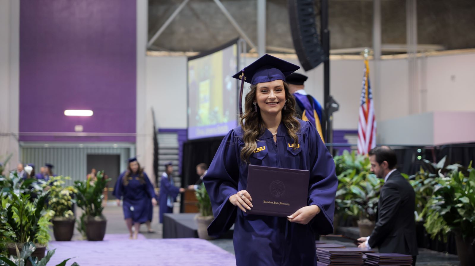 graduate walking across the stage after recieving diploma