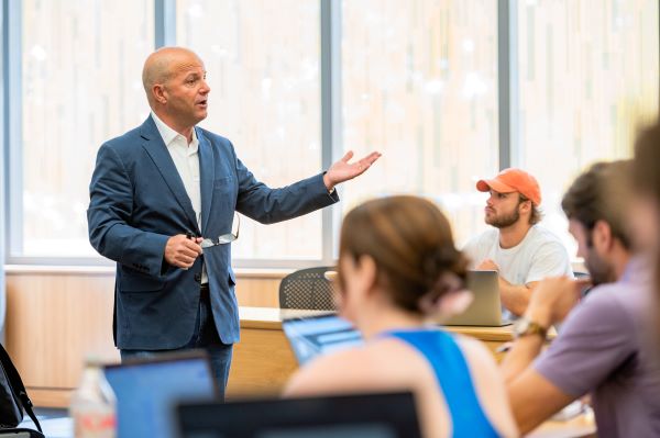 Professor raises hand while speaking to class