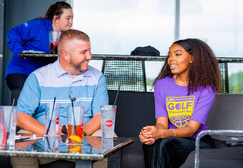 Professional talks with sales student at Top Golf