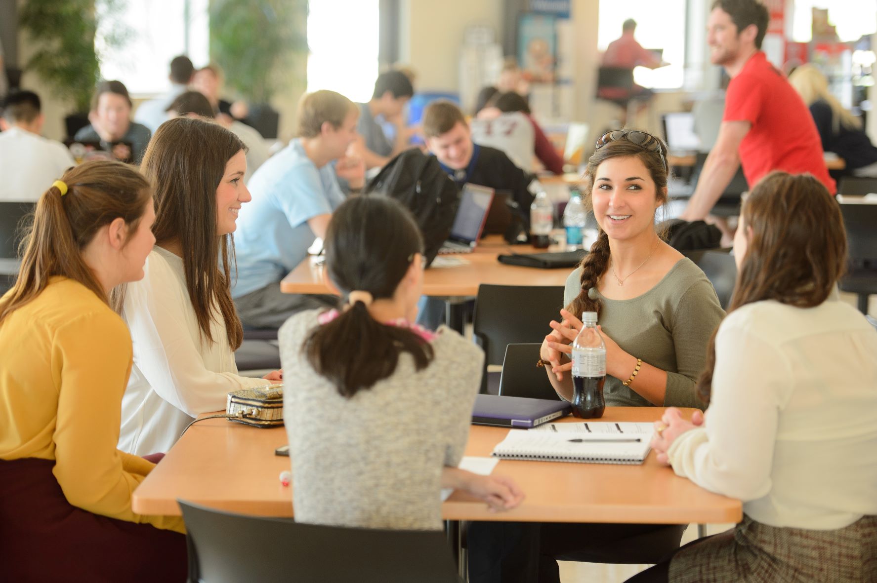 Female students talk around a table in the BEC Rotunda