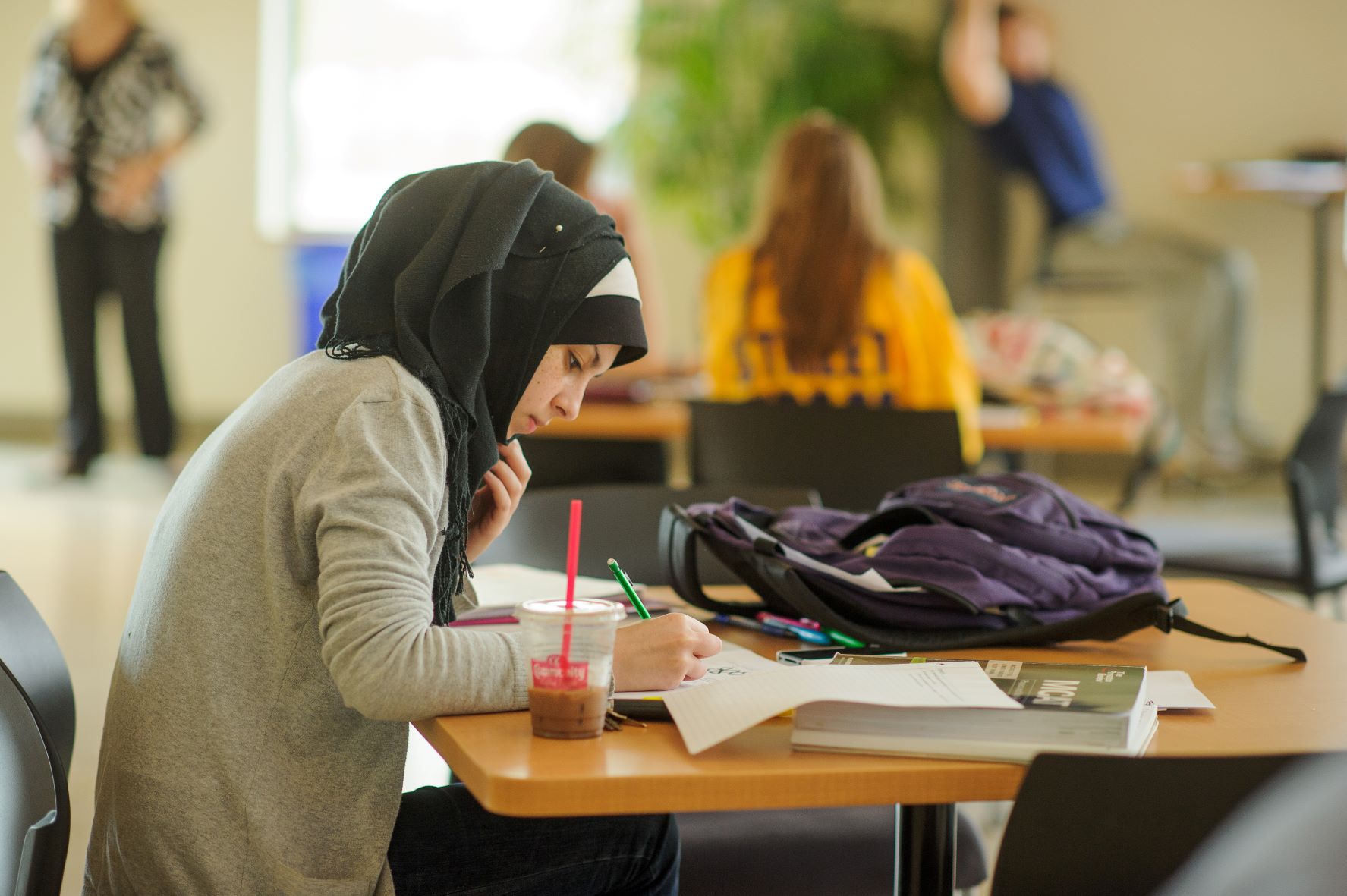 Student writes at a table in the BEC Rotunda