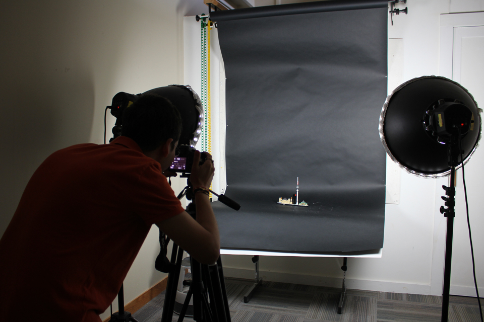 student taking a photo of a model against a black backdrop